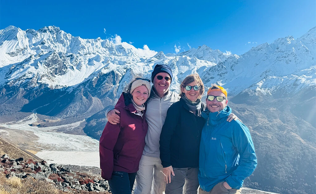Happy trekkers posing with the stunning snow-covered Langtang mountain range in the background