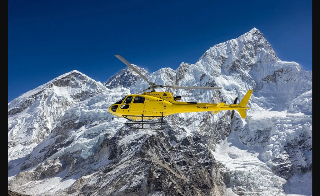 helicopter flying above towering, snow-capped mountains near Kala Patthar and Everest.
