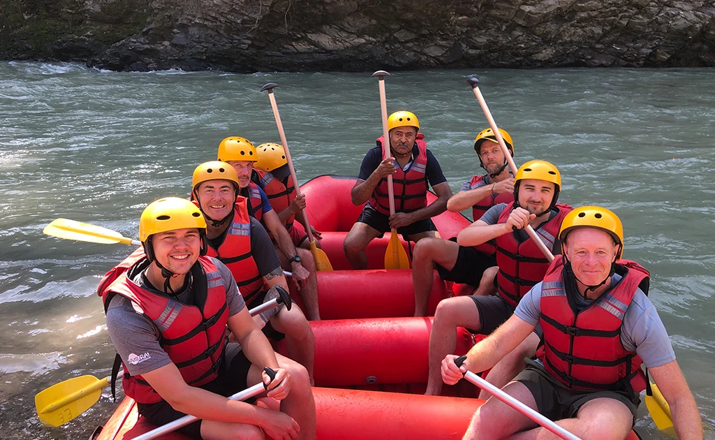 Rafting group smiling and posing in a red raft before starting their Trishuli River adventure.