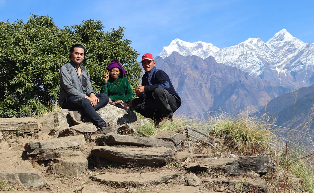 Two travelers pose with a local elderly woman in traditional attire