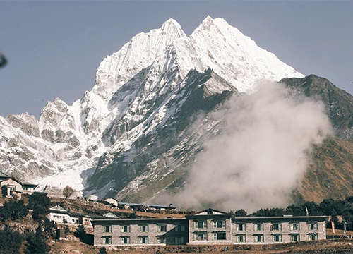 Mountain lodge beneath towering snowy Himalayan peaks.